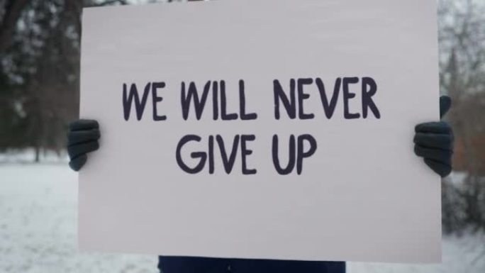 抗议男子举牌反对政治，上面写着“我们永不放弃”