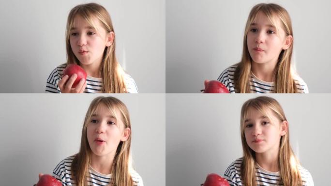 一个穿白色衣服的小女孩正在吃一个多汁的大红苹果。女孩咬了一块红苹果