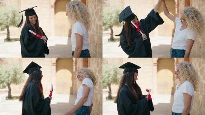 两名女母亲和毕业女儿在校园大学举手高五