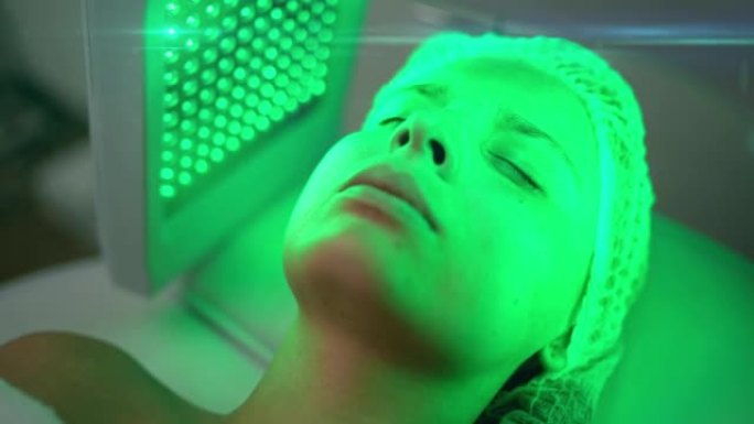 年轻女子接受绿色发光二极管面部治疗