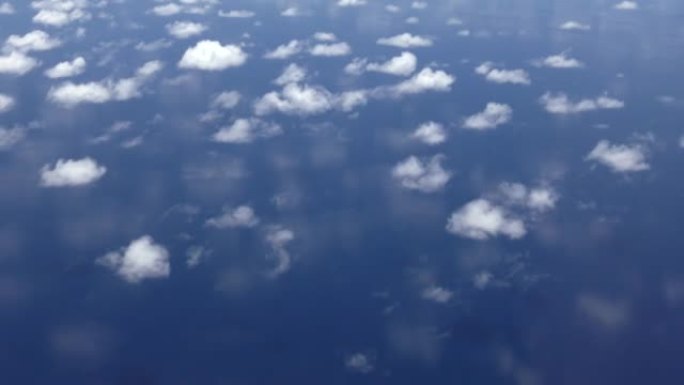 云彩飞过蓝色的海洋，反射在水的空中视图表面。印度洋