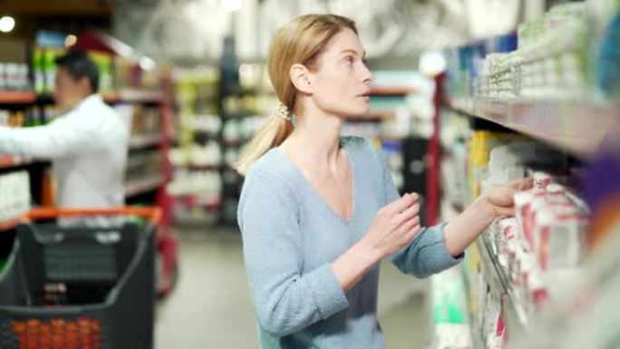 年轻女子选择超市商店货架上的商品个人护理卫生用品，女性选择家用化学品。犹豫不决，