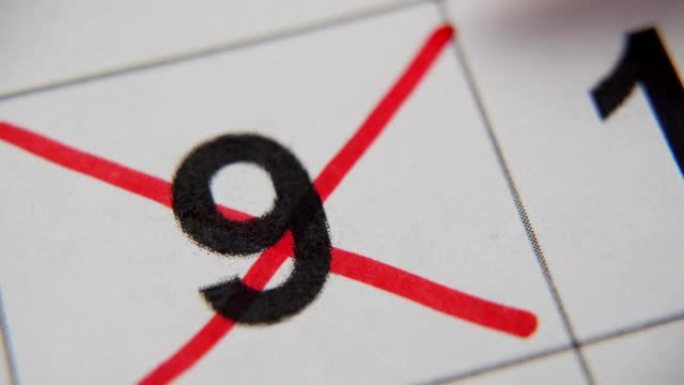日历中的第9个数字在白纸上的宏中用红叉划掉。计划、笔记、会议日历。商业日历。日历中注释的标记。
