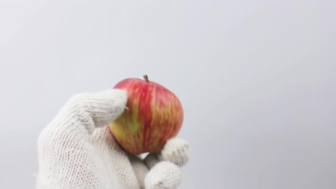 农夫拿着一个苹果，戴着白色背景的pov手套。收获概念。天然红苹果。