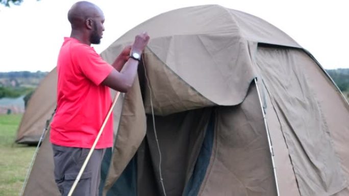 一名黑人男子和他的白人助手为过夜游客露营搭建了一个帐篷