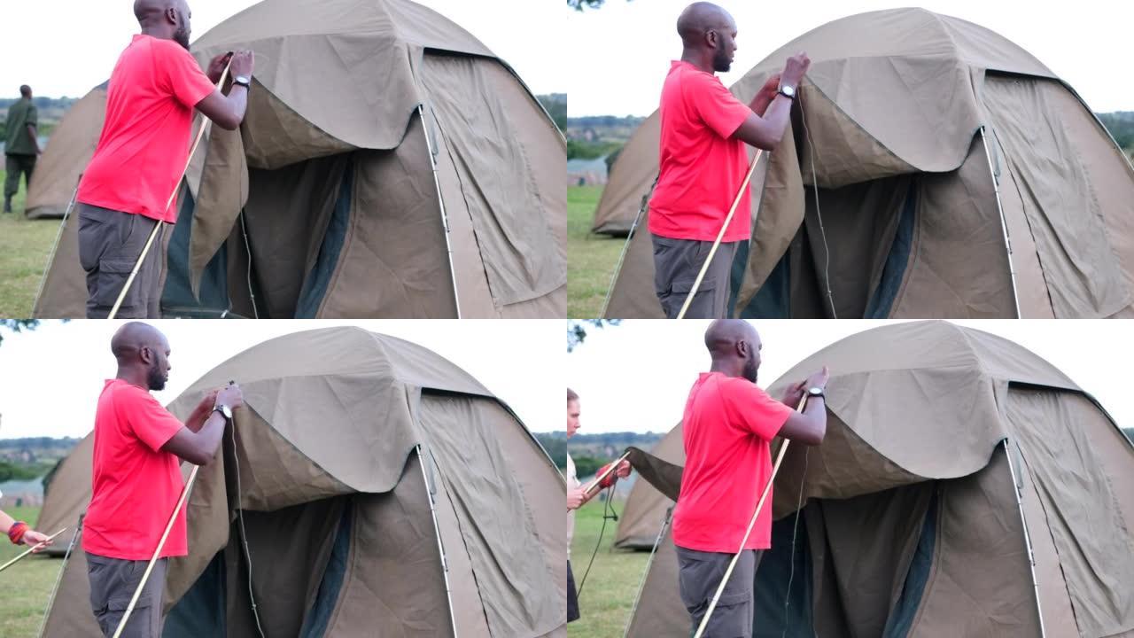 一名黑人男子和他的白人助手为过夜游客露营搭建了一个帐篷