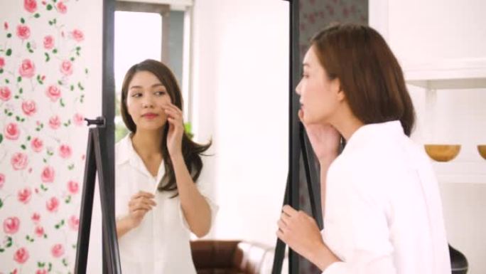 美丽的年轻亚洲女子在镜子前化妆