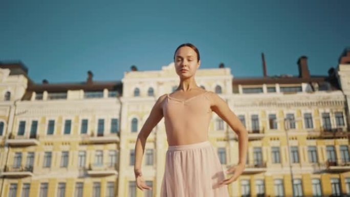 优雅的芭蕾舞演员在城市举起双手进行舞蹈动作