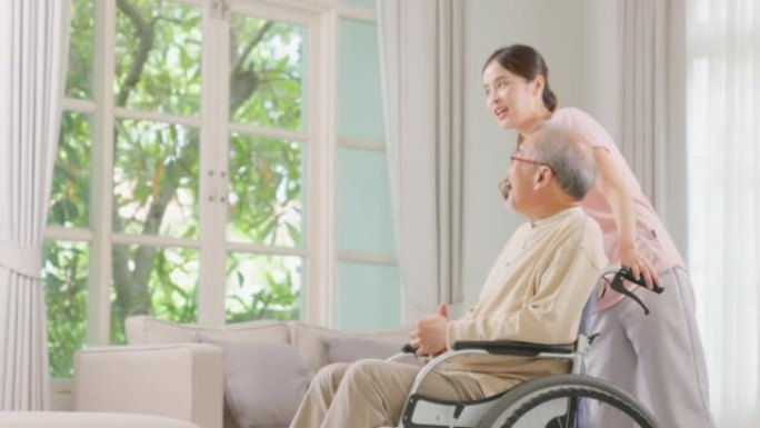 一名高级男子患者坐在轮椅上，由一位年轻的女士护理人员支持和协助。照顾者与心满意足的老年人交谈