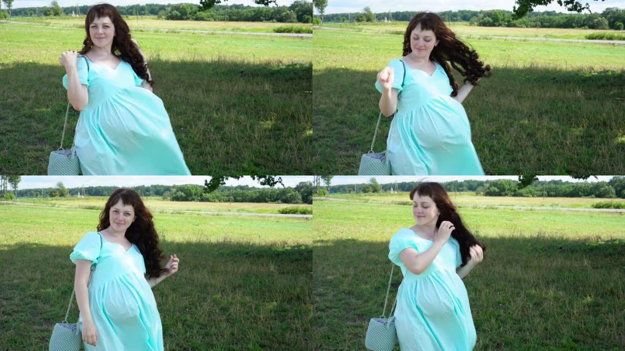 穿着蓝色连衣裙的美丽孕妇在公园散步。快乐怀孕。