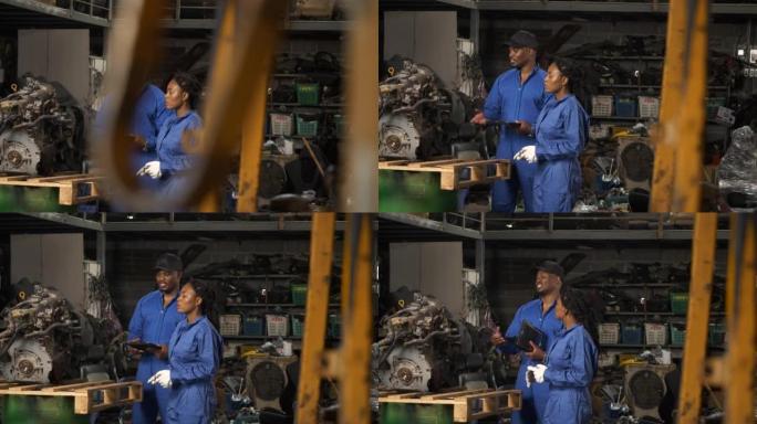 非裔美国男女合伙人拥有汽车修理厂。背部男女修理工检查汽车维修。两个机械师在检查汽车发动机。 一男一女