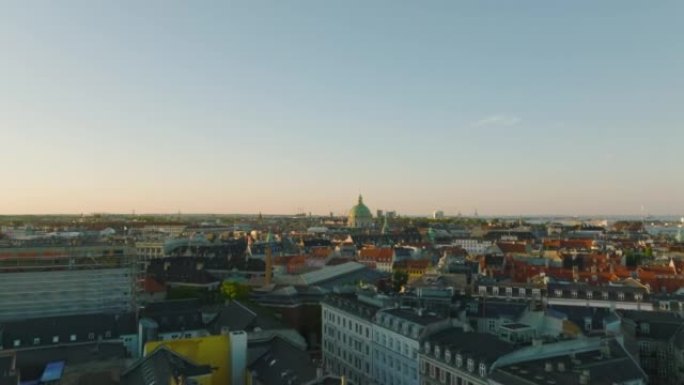 黄金时段城市历史建筑的空中提升镜头。宏伟的弗雷德里克教堂圆顶高耸在周围的开发项目之上。丹麦哥本哈根