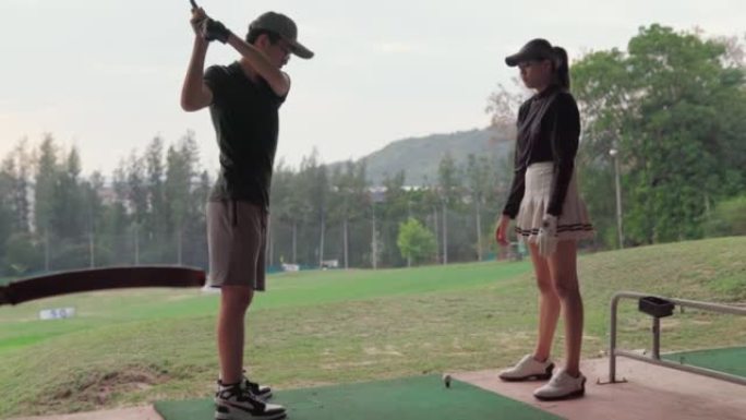 活跃的女高尔夫球手教男孩如何在高尔夫球场上打高尔夫球