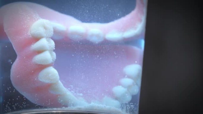 一杯清洗液内人造牙齿的特写镜头。