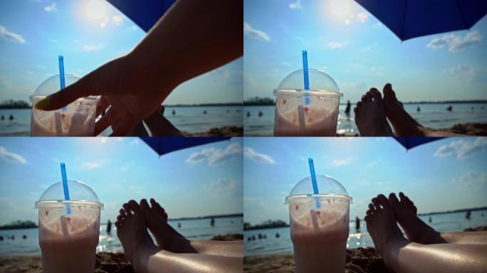 手在女人的腿和海滩的背景上放了奶昔