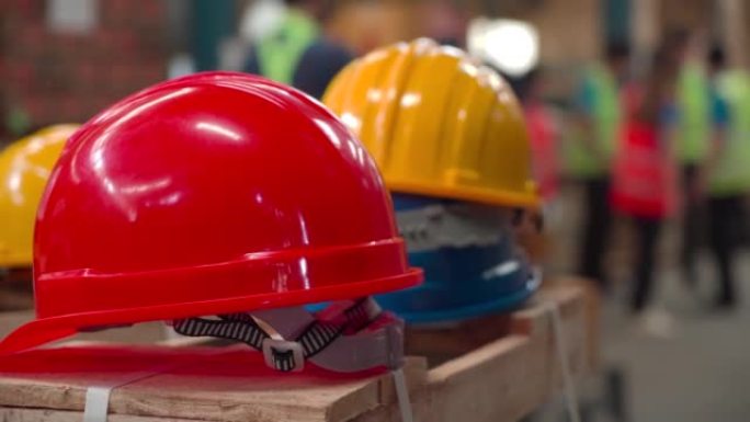 工人的特写手提头盔，许多安全帽放在仓库商店的纸板箱上，为员工准备，红色，白色和黄色硬头盔，供工程师检
