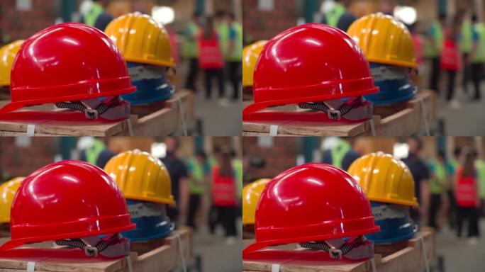 工人的特写手提头盔，许多安全帽放在仓库商店的纸板箱上，为员工准备，红色，白色和黄色硬头盔，供工程师检