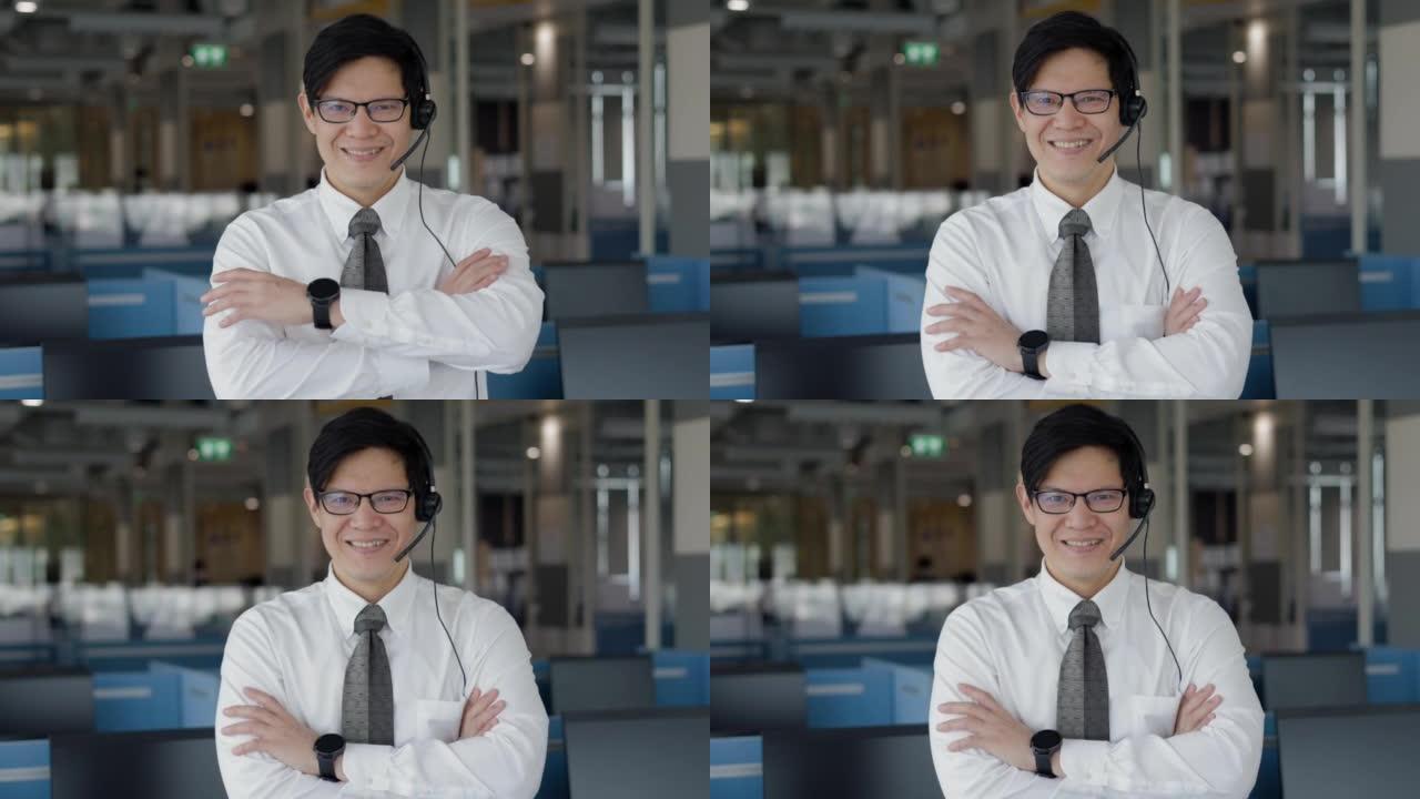 智能成功亚洲男性客户服务代表的肖像，带耳机，显示OK- sign，笑脸并站在呼叫中心房间。看着镜头。