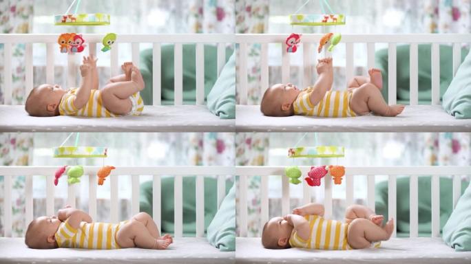 婴儿床里三个月的婴儿看着移动旋转木马，微笑着。