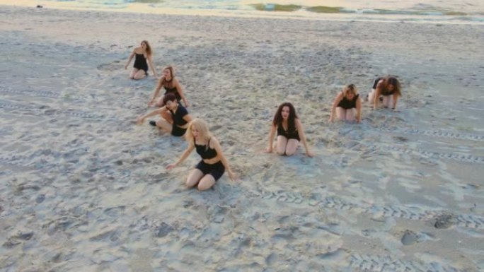 日落时在海洋海滩与教练一起在户外练习瑜伽课的七人组