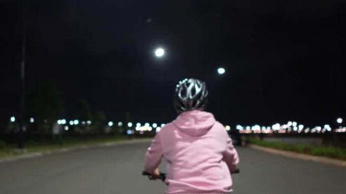 亚洲穆斯林女子晚上在城里骑车