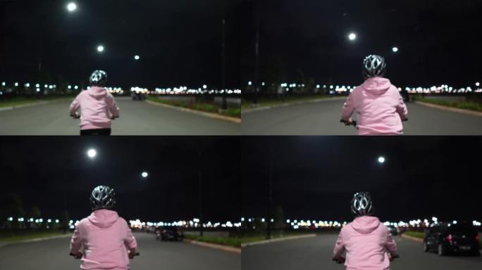 亚洲穆斯林女子晚上在城里骑车