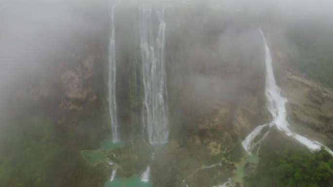 汹涌的瀑布被雾覆盖，被树木和岩石包围