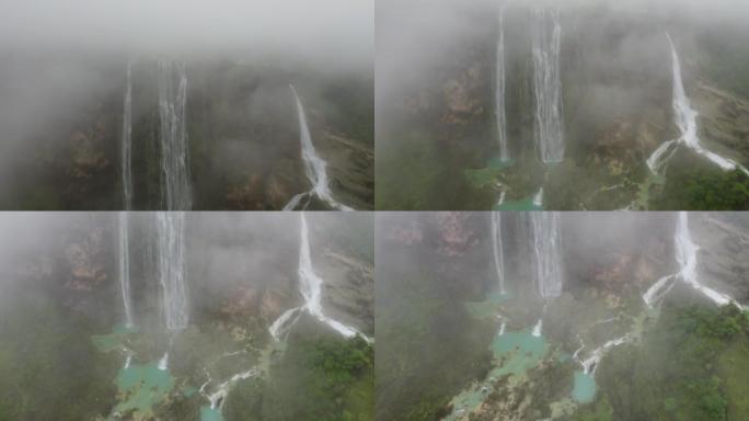 汹涌的瀑布被雾覆盖，被树木和岩石包围