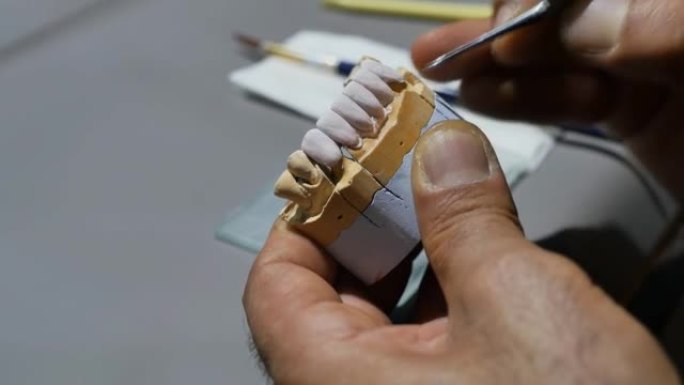 牙科技师的手用前牙制作下颌假体。师傅在工作时用软刷清洗假牙。人造牙齿的概念