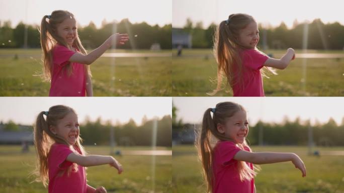 快乐的小女孩在春天的草地上挥舞着飞舞的绒毛