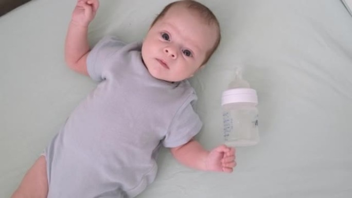 婴儿奶瓶在家里的婴儿婴儿床，肖像婴儿饱食的婴儿刚刚喝了奶粉。