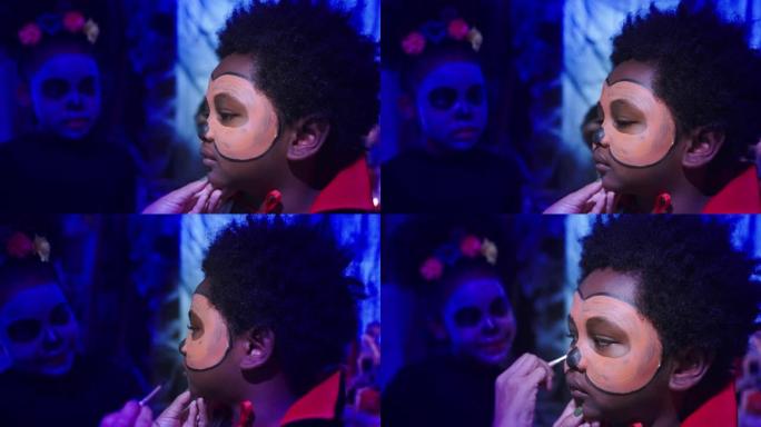 在万圣节节日中，黑人男孩和女孩在亚洲母亲的脸上画得很开心。房间里装饰着南瓜jack'o灯笼，蜘蛛，蜘