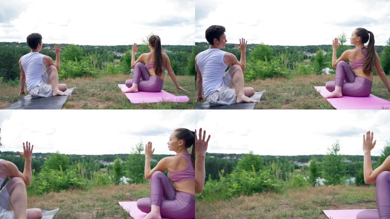 男人和女人坐在草地上的瑜伽姿势中扭曲身体