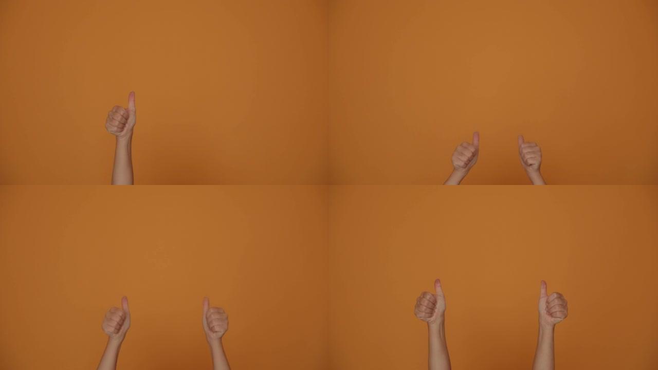 女人的手指竖起大拇指在橙色工作室背景上跳舞