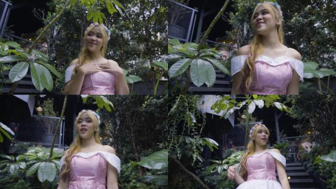 穿着粉红色连衣裙的金发公主在绿叶和鲜花的森林城堡中玩耍