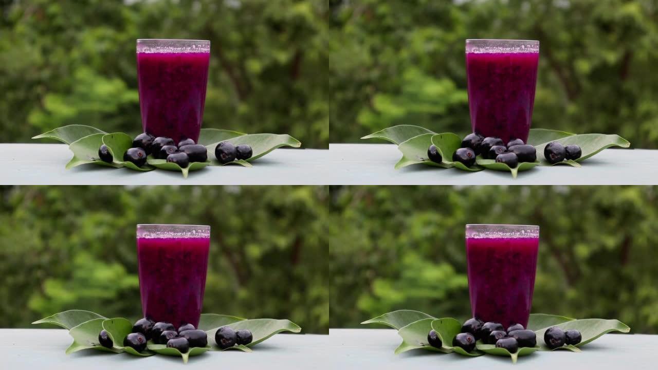 在带有复制空间的木制背景上隔离的水果和叶子的玻璃杯中的Jamun或黑梅汁，也称为Malabar Pl