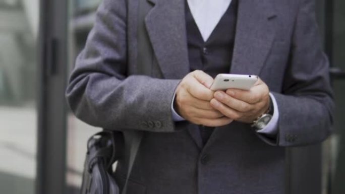 穿着优雅西装的男人在智能手机上打字，在社交网络中与女性聊天，在网上信使中与朋友或亲戚交流，回复电子邮