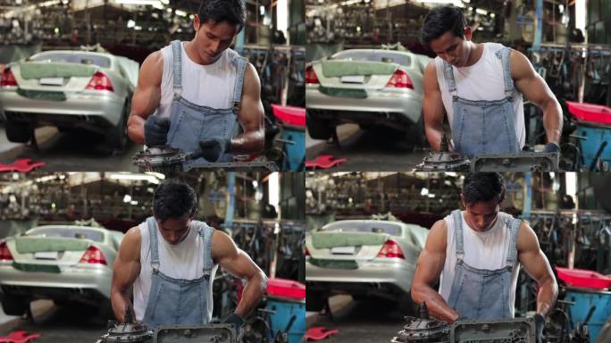亚洲男性汽车工程师在旧工业汽车车库车间固定发动机动力传动齿轮箱