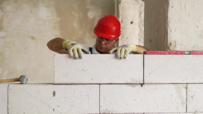 瓦工或泥瓦工砌砖以建造蒸压加气混凝土砌块的墙。砖砌工人承包商在施工现场用泡沫混凝土砌筑砌块。