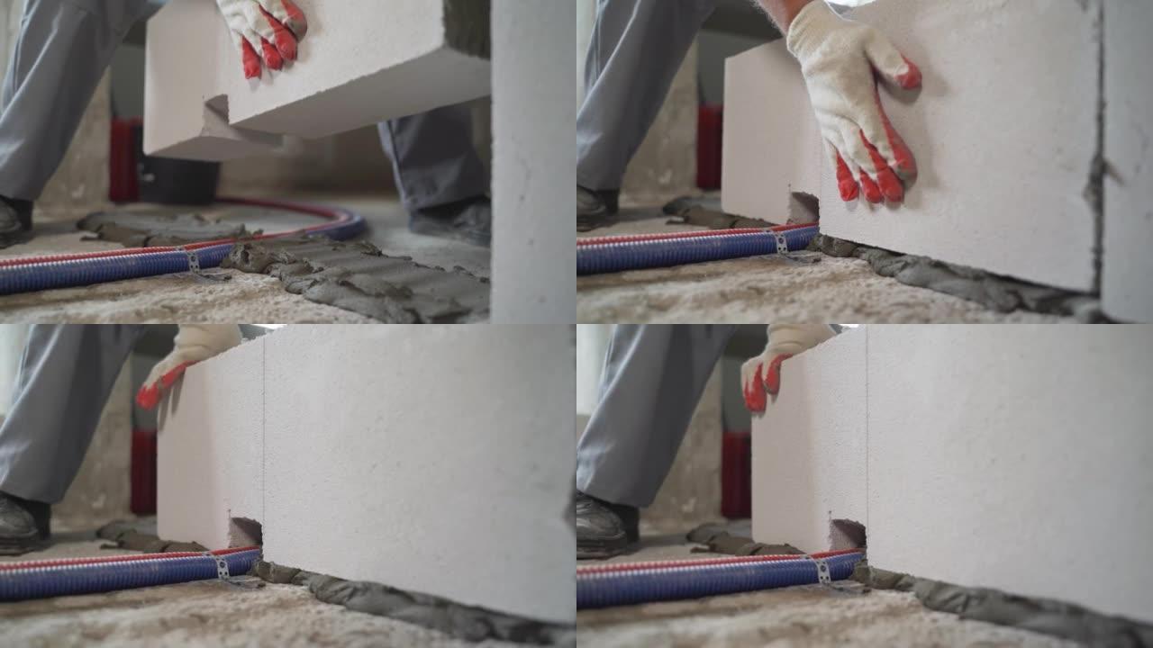工人把加气混凝土块放在胶水上。白色块放在地板上，用于建造隔板。块被粘在地板上的胶水上。