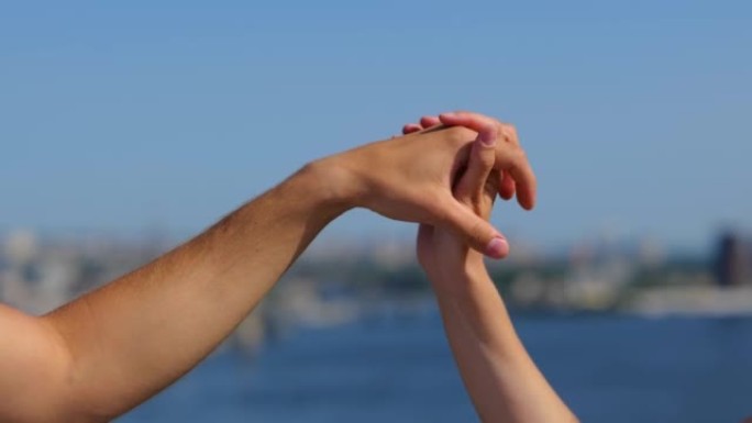 男性和女性的手在街道上连接。无法辨认的男人和女人的手在户外空中握着。一对浪漫的人在外面触手的特写。爱