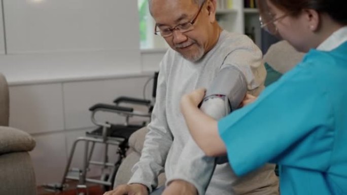 亚洲护理医生检查老年患者使用血压计。护士探访并照顾病人，老人在客厅检查老年老人，保健保险理念。