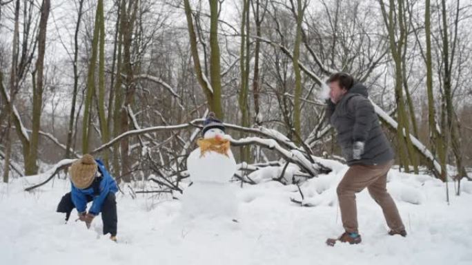 成熟的父亲和儿子在冬季森林的雪战中。爸爸和孩子玩得开心，一起度过美好时光。