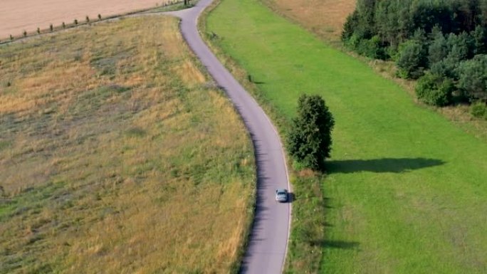 欧洲自然乡村乡村景观的公路旅行旅行度假。鸟瞰车在树木和农田之间的乡村道路上行驶。波兰乡村的房子村。