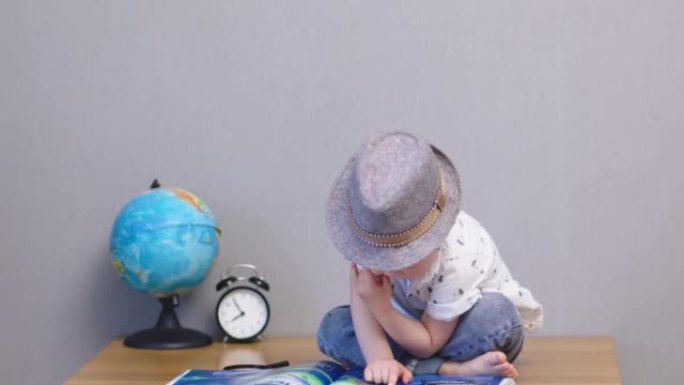 帽子里可爱的男婴坐桌阅读大书儿童教育理念