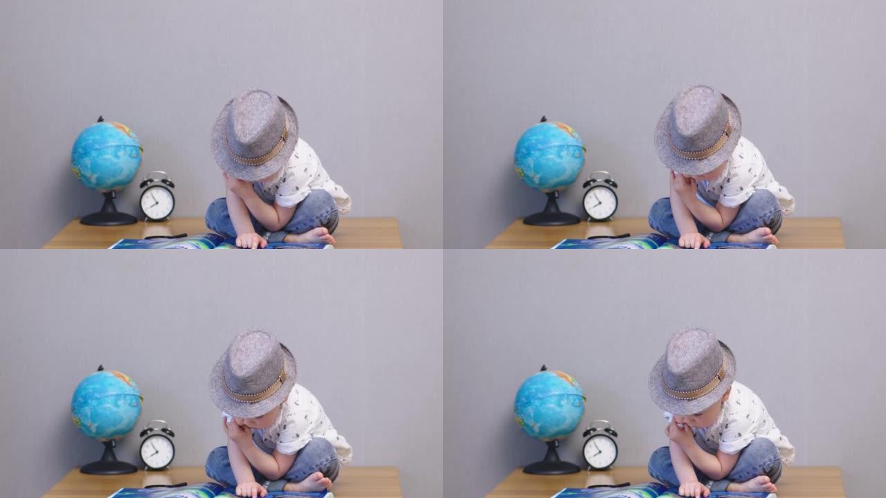 帽子里可爱的男婴坐桌阅读大书儿童教育理念