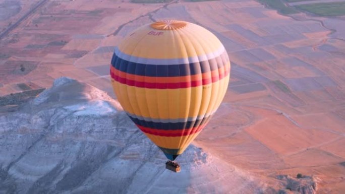 巨大的黄色热气球在清晨降落在Goreme附近的卡帕多细亚山谷。