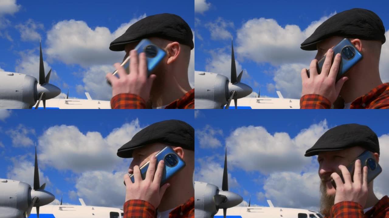 一名戴着胡须的男子站在蓝天下的机场，在飞行前打来电话。他的飞机启动引擎起飞。那个人正在打电话。