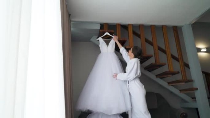 新娘从衣架上取下婚纱，摆姿势