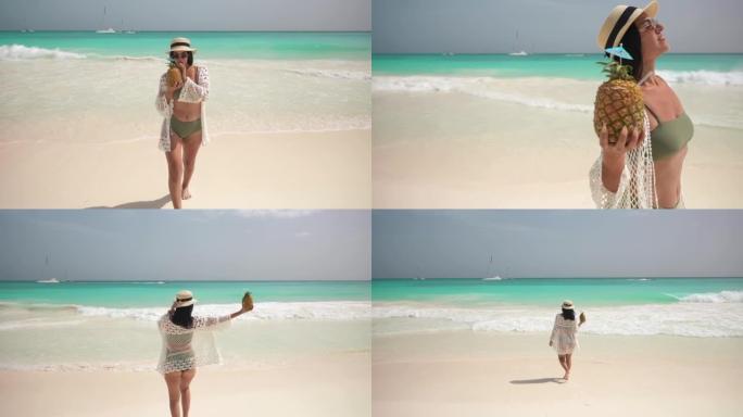 美丽的拉丁女孩喝pina colada鸡尾酒，然后在海滩上走向相机。加勒比海的绿松石水和白沙。在天堂